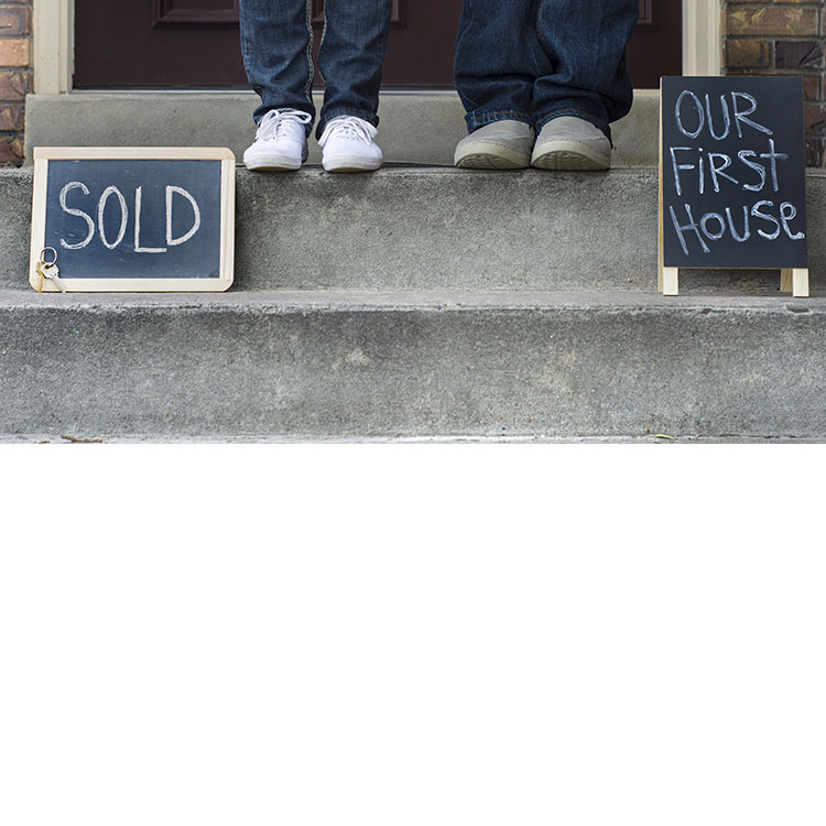 two people standing in front of their first house