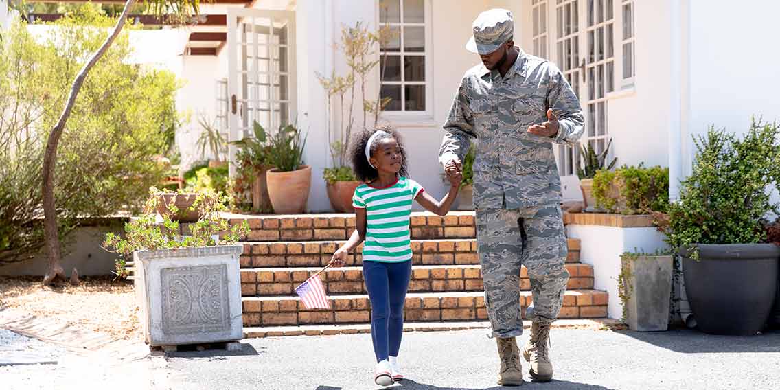 military personnel with daughter in front of home