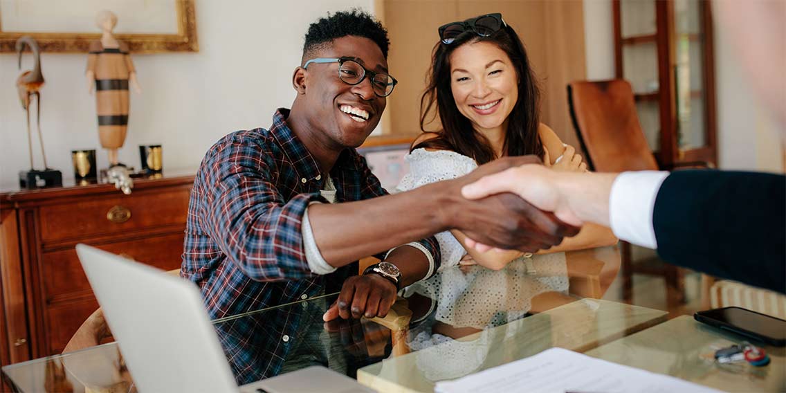 couple shaking hands with real estate agent