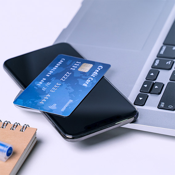 credit card and mobile phone stacked on top of laptop