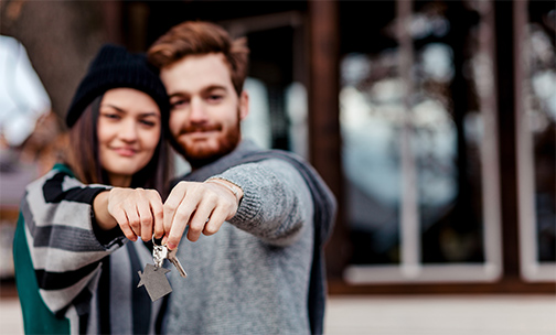Man and woman holding a set of keys with a house charm on it.