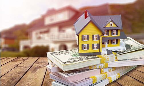 miniature home sitting on stack of money