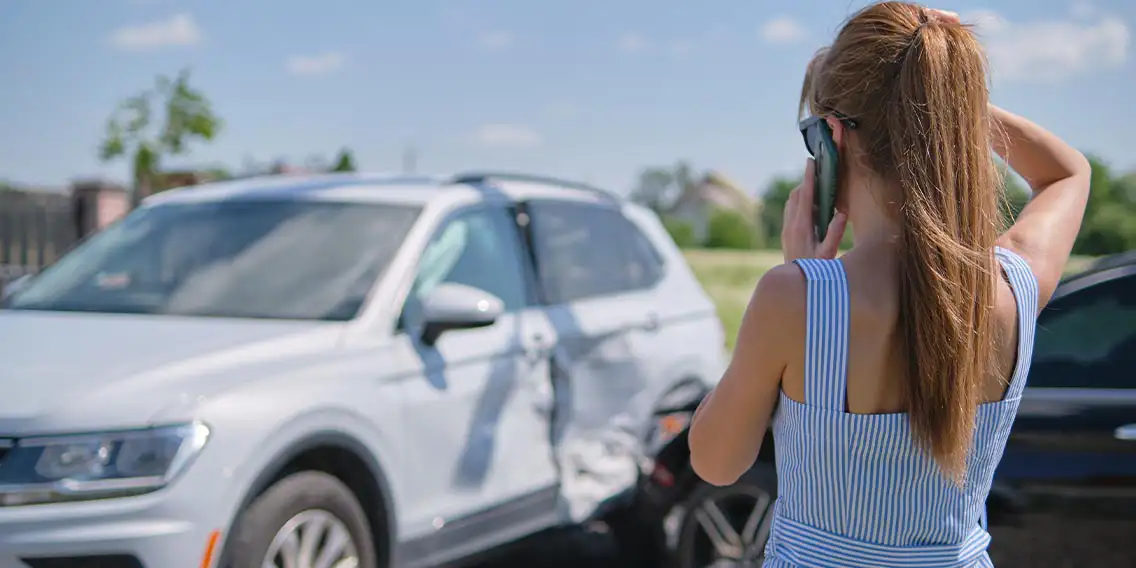 a girl talking on phone while standing near the car