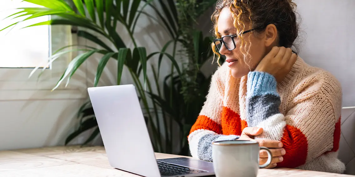 Women with a coffee mug reading laptop screen