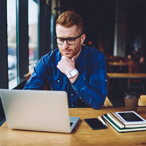 man in coffee shop looking at laptop