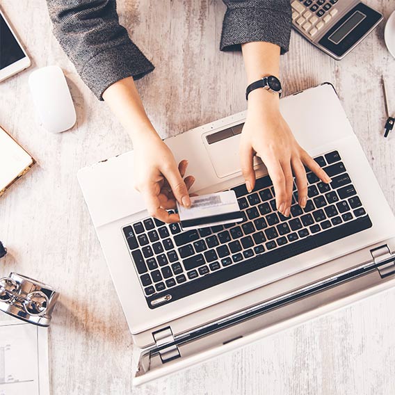 woman typing credit card information into laptop