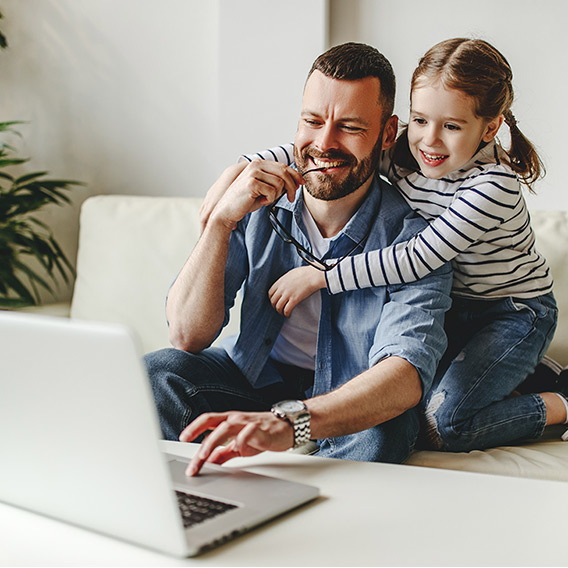 happy family a businessman father working at a computer and his child daughter at home