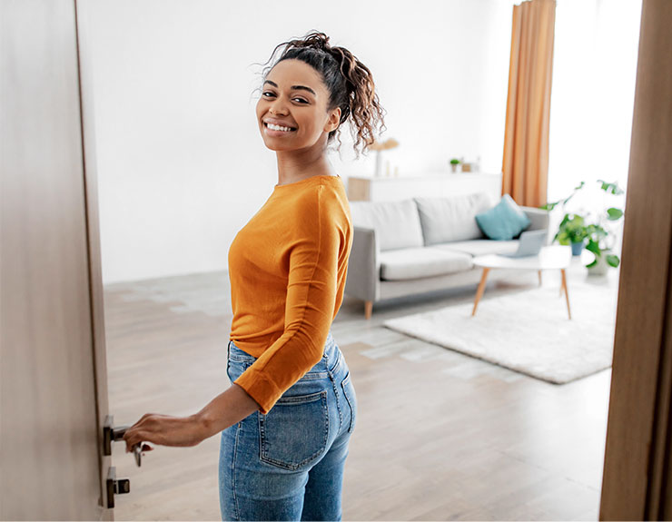 Cheerful African American female opening door entering her home