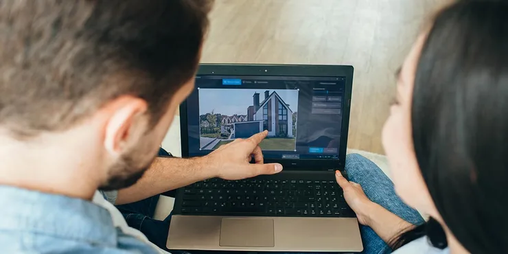 Couple looking at a house on a laptop.