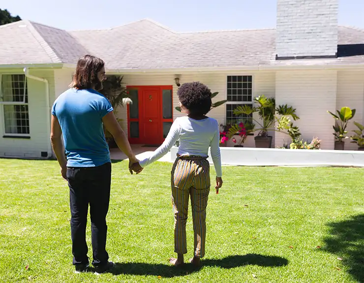 couple holding hands in front of their new home