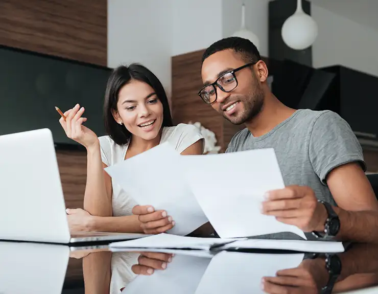 Cheerful loving young couple using laptop and analyzing finances