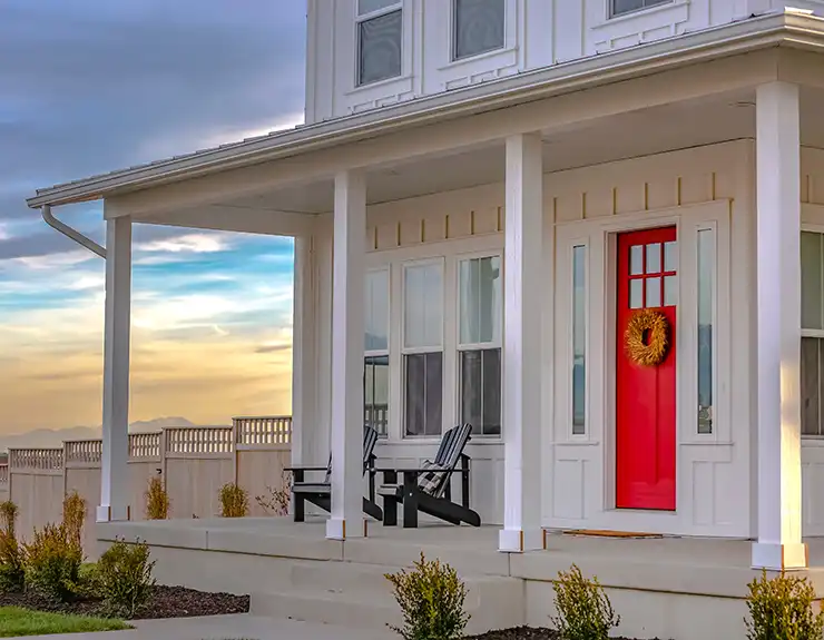 Facade of home with red door porch stairs and yard.