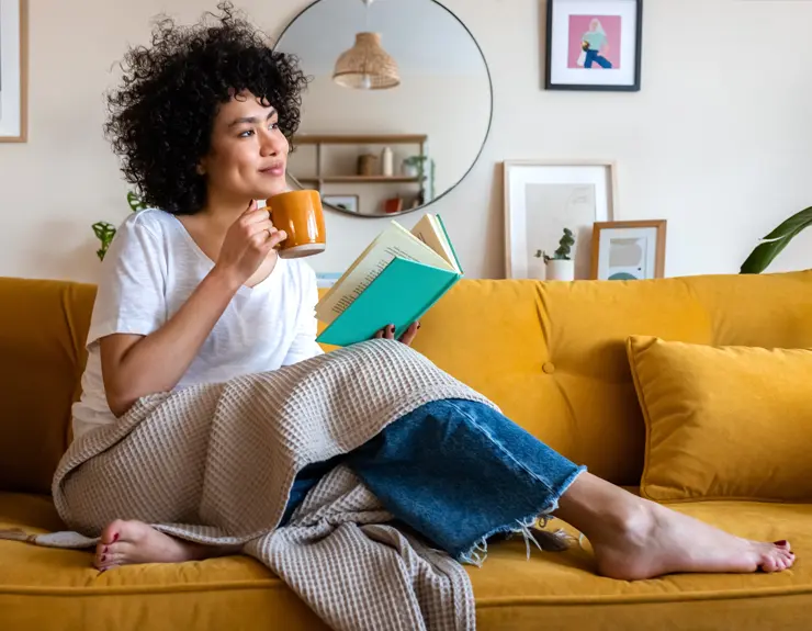 Lady reading a book with coffee mug in one hand
