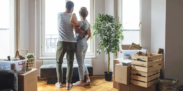 Couple unpacking and looking out window of home.