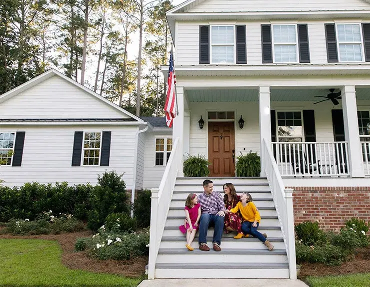 family sitting in front of a house