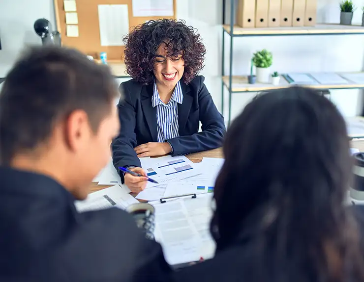 Young beautiful couple applying for mortgage. Sitting smiling happy meeting with real state agent signing mortgage loan at bank