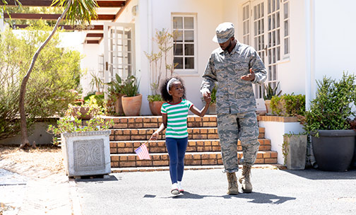 military personnel with daughter in front of home