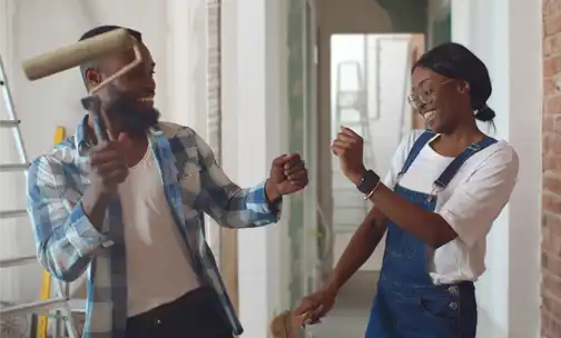 happy couple dancing while painting their home