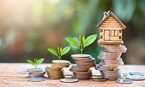 tiny wooden home on stack of coins