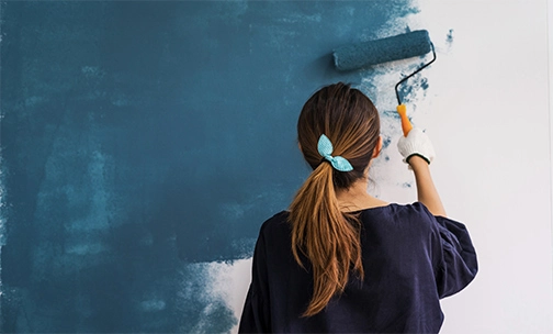 Woman painting wall with a paint roller.