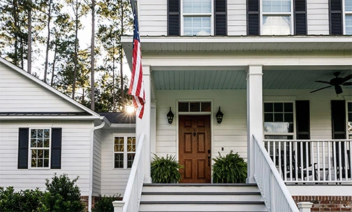 child with American flag running up steps of home