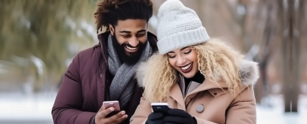 African American couple smiling while interacting with their mobile devices