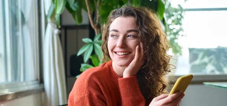 a woman smiling while holding a phone