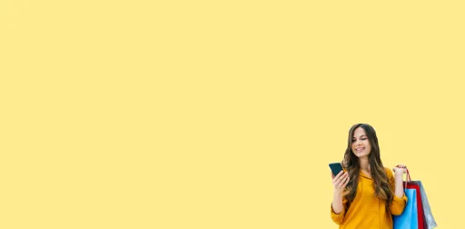 Women looking at the mobile phone while carrying shopping bags in other hand 