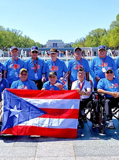 A group of Puerto Rican military veterans holding a Puerto Rico flag in front of the Lincoln Memorial.