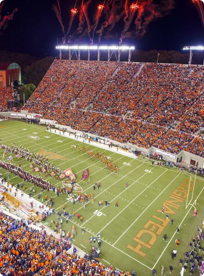 A wide aerial view of Lane Stadium at night celebrating and honoring the military community with illuminated stadium lights.