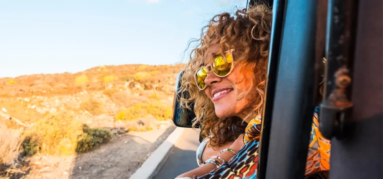 Happy women smiling and looking back from the cars window