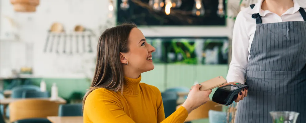 A lady wearing yellow top smiling while paying