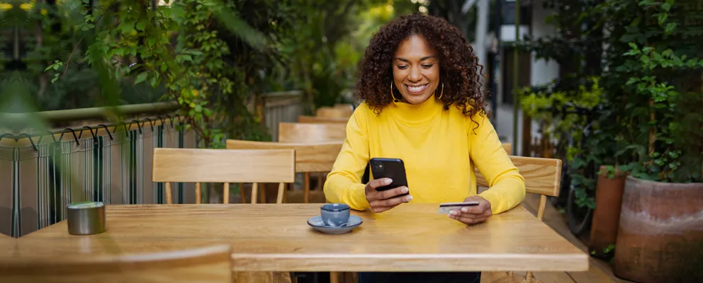 Women looking at phone screen with credit card in other hand.