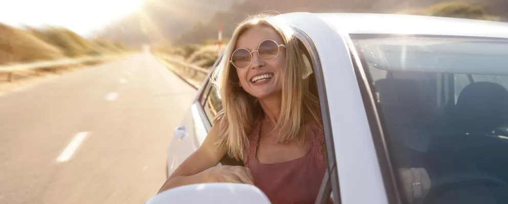 a girl looking out of the car from window and smiling