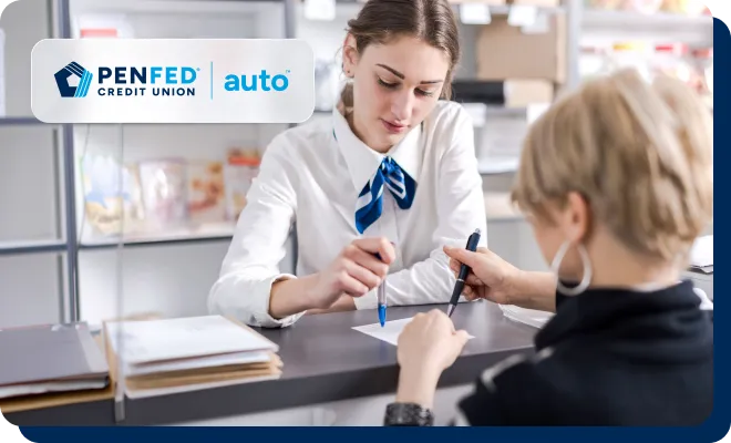 A agent guides a member through signing paperwork for a car title at a service counter.