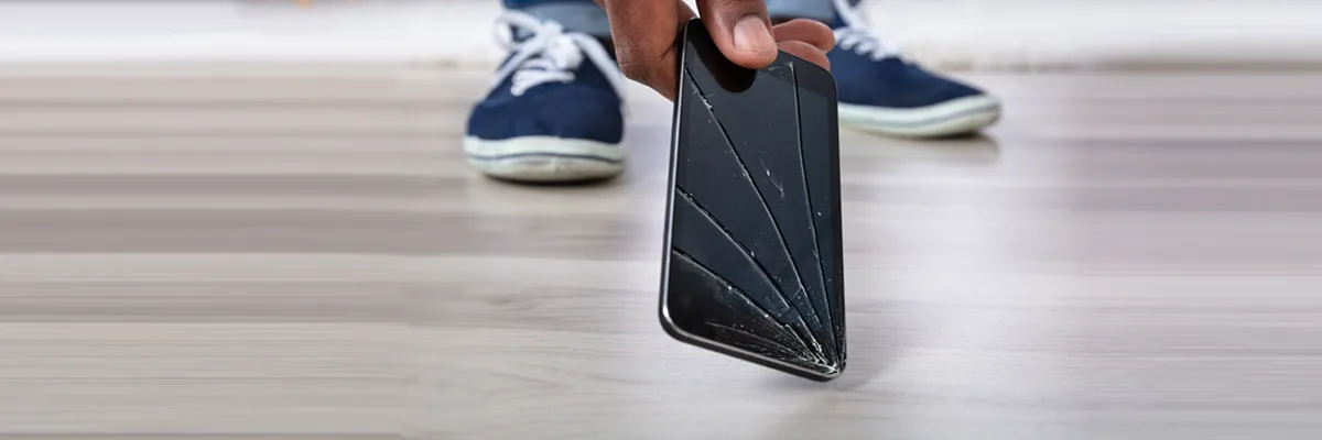 a person holding a broken mobile phone on floor