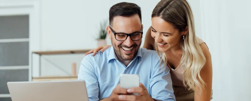 couple smiling while doing the payment on phone