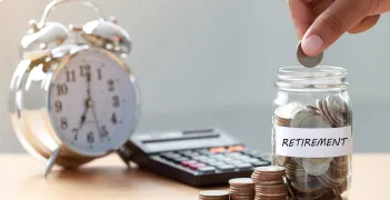 calculator and glass jar labeled "RETIREMENT" filled with coins
