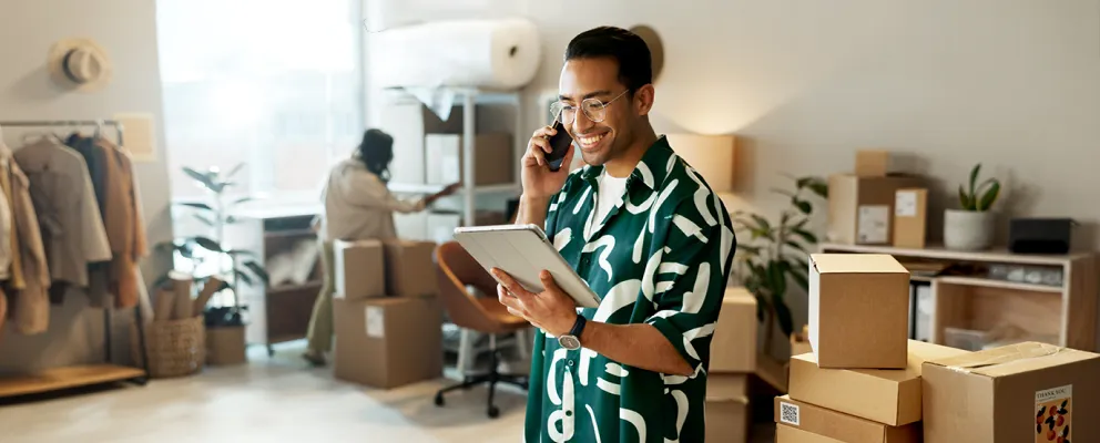 man talking on phone while holding a tab in hand and smiling