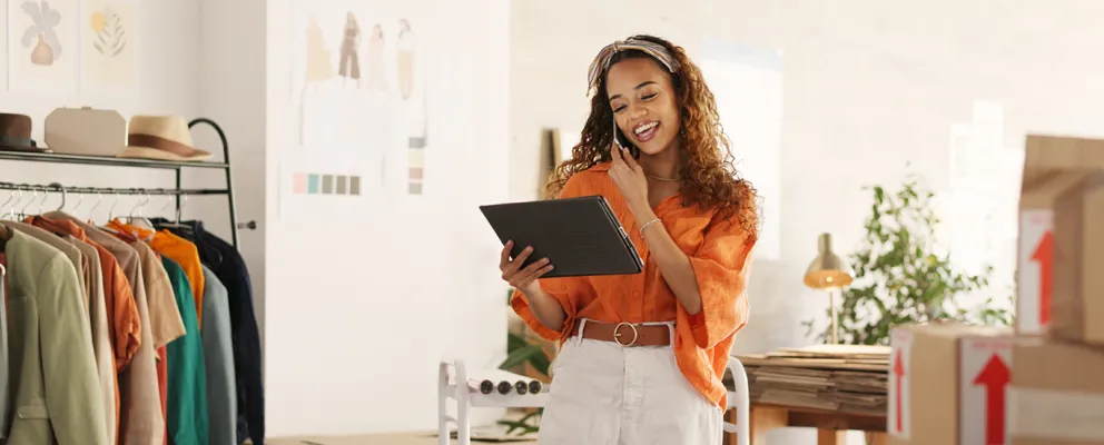 woman talking on phone while holding a tab in hand and smiling