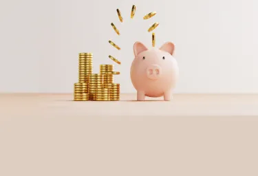 Gold coins falling into piggy bank