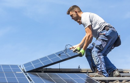 man installing solar panels on a roof