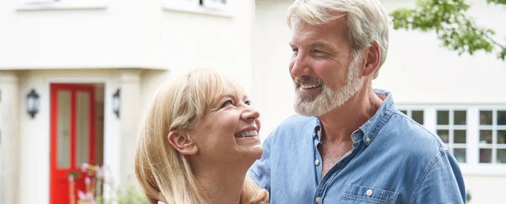 smiling couple in front of their new home