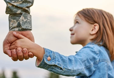 military personnel holding the hands of his daughter