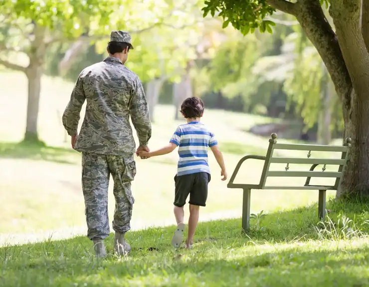 military parent walking hand-in-hand with their child