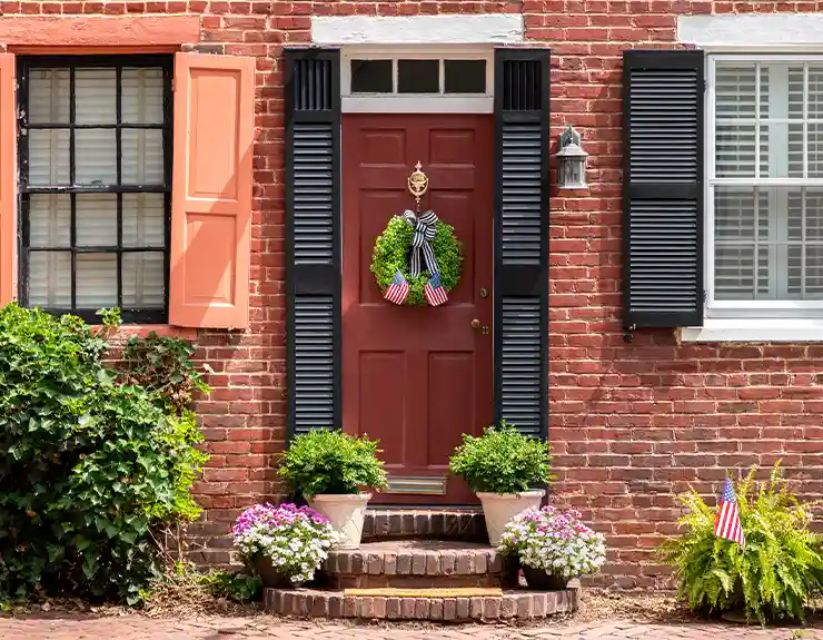 front of home with wreath on the door and american flags