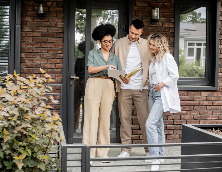 couple speaking to a real estate agent in front of a house