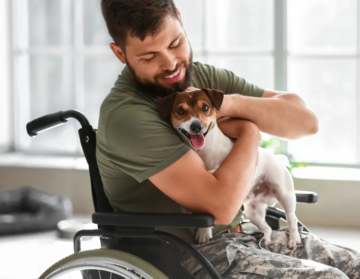 military service member in a wheelchair hugging his dog