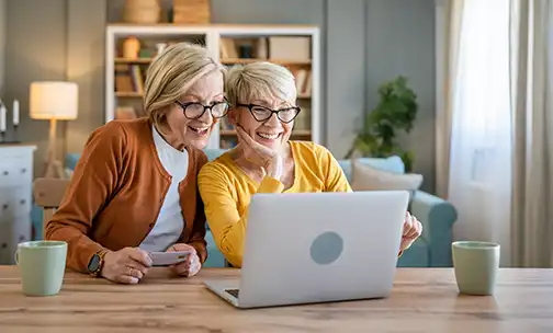 Senior women two females hold credit card online shopping at home
