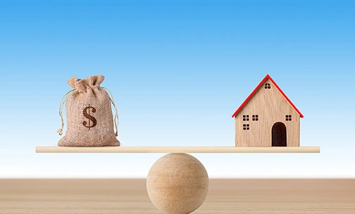 scale with house on one side and bag of money on the other perfectly balanced
